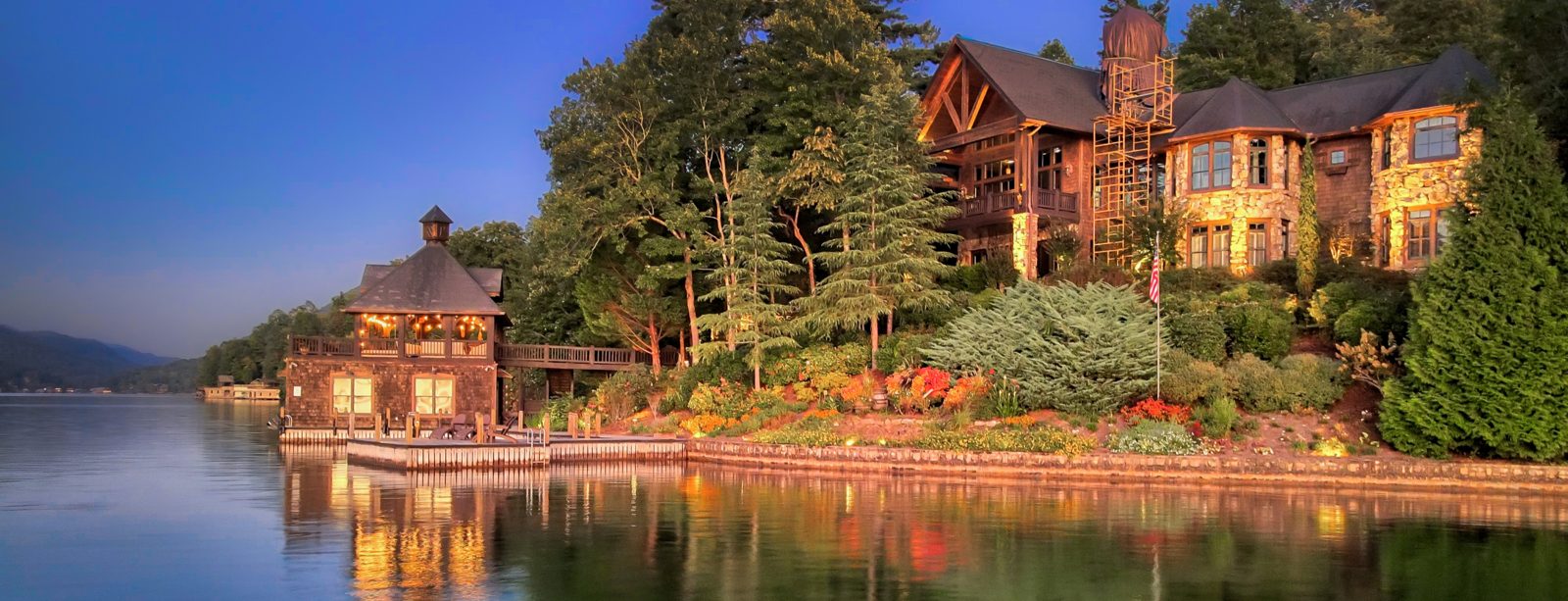 Lake Burton home at sunset with a lit boathouse and landscape lighting